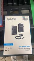 Front of the retail box showing BOYA BY-WM4 Pro wireless microphone system with transmitter, receiver, and lavalier mic image and compatibility icons.