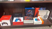 Photo showing all boxed items lined up on a shelf including controllers, headphones, and TV Box