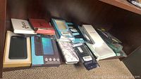 Overview of multiple assorted phone cases, some in packaging, laid out on a shelf