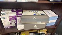 Shelf with boxed Philips Avent manual and electric breast pumps, unopened Grow milk warmer box, and duo Bella pump box.
