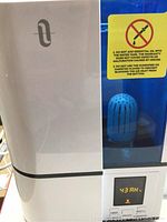 Front view of the Taotronics humidifier showing white and blue body, transparent water tank with blue filter inside, LED display and control buttons.