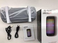 Unboxed speaker with accessories: charging USB cable, aux 3.5mm cable, user manual, original product box