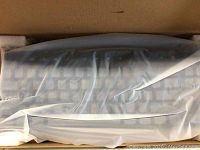 Mechanical keyboard still in protective plastic inside box, showing full keyboard layout.