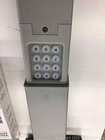 Photo of the universal garage door wireless keypad with grey plastic body and illuminated keypad showing digits 1-9, *, 0, #