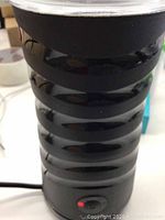 Front view of black, ribbed VAVA milk frother with power indicator light