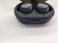 Close-up of black Tranya T3 wireless earbuds in black charging case with glossy silver triangular touch surfaces, showing L and R earbud indicators.