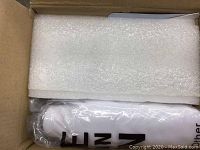 Partially visible white projector inside protective packaging in box