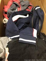 Top view of folded men's sweaters and baseball hats packed in a box