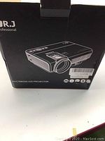 Box for DR.J Professional multimedia LED projector, black with white outline of projector and brand logo.