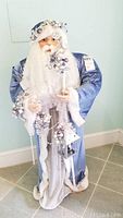 Full view of the Father Christmas figure standing on floor, showing blue robe, white fur trim, beard, candle holder and staff with crystal tip.