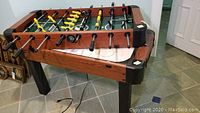 Combined foosball top attached to air hockey base viewed at angle