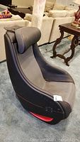 Front left angle showing black and grey massage chair with red stitching, mesh fabric seat and control buttons on left arm.