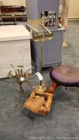 Overall lot view showing adjustable brass music stand, glass top table, footstool, and decorative box