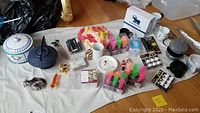 Photo showing assortment of items including cookie jar, kettle, figurine, Hamilton Beach sandwich maker, coffee cups, flashing party shooters, tea lights, and holiday plates