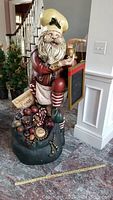 Full side view of chef Santa Claus statue sitting on Christmas Feast sack with candy, toys, and food items.