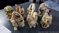 Photo showing all seven handcrafted resin Asian elder figurines on a dark surface, displaying their varied traditional attire and poses.