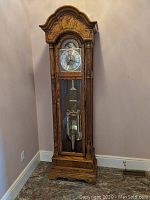 Full front view of oak grandfather clock against wall