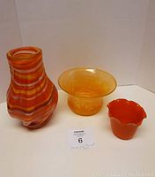 Photo showing all three items together: orange swirl vase, handblown bowl, and flower pot