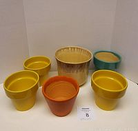 Six flower pots arranged in two rows against a white background: three yellow, one orange, one aqua around 5 inches tall and one larger yellow-brown pot with glaze on rim.