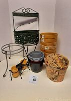 Full view of all the flower pots and holders arranged showing terracotta pots, plastic pots, metal stands, miniature pots in insect holders, and green ornate metal holder.