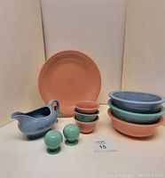 Full view of all pieces including 12 inch salmon pastel chop plate, 3 pastel 8 inch serving bowls, 3 custard cups, blue gravy dish, and green salt and pepper shakers arranged on white background.