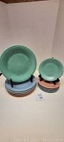 Photo of stacks of pastel Fiestaware plates including six 11-inch dinner plates and six 7-inch salad plates, displayed on black plate stands.