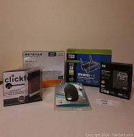 Photo showing all five items together including the boxes for Netgear router, WD My Passport hard drive, Clikfree backup solution, Logitech wireless mouse, and Linksys router.