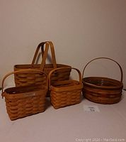 Four Longaberger baskets arranged on a white surface showing different shapes and sizes, with plastic liners in some.