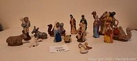 Overview photo of all 16 ceramic nativity figures arranged in a group showing human figures and animals including camel, donkey, sheep.