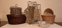 Front view of various baskets including wicker, metal wire with woven inserts, and glass bowl basket in a row.