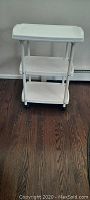 Front view of white plastic 3-shelf rolling cart with removable top shelf