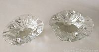 Pair of clear glass candle holders with irregular folded edges shown from above