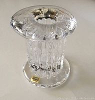 Side view showing vertical ribbed textured glass column and round thick base with sticker.