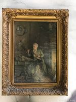 Full view of antique framed canvas print showing elderly man seated by fireplace playing cards, ornate gold frame visible.