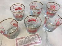 Six clear glass tumblers arranged in two rows on white surface, each featuring red TTC streetcar prints and gold rims