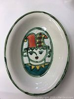 Top view of oval ceramic bowl showing the colorful jester face design painted inside.