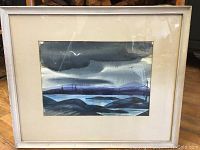 Full view of the framed watercolor painting showing the coastal scenery and the signature.