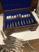 Full view of cutlery set displayed in blue velvet-lined wooden box with cake server and knives outside box.