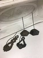 Photo showing four antique metal note holders with different base shapes and decorative designs, two with hexagonal bases and two with flat ornate cast bases, all with tall spikes for holding notes.