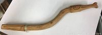Full length photo of the carved wooden stick showing slight curve and natural wood tone.