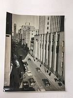 Black and white photograph showing an elevated view of a busy Toronto street with vintage cars and buildings including a clock tower.