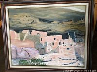 Full view of vintage framed oil painting showing adobe pueblo buildings under a cloudy sky, signed LT.