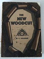 Front cover of 'The New Woodcut' showing the title, author name, and some handwriting on the cover. Book is softcover with tan and brown woodcut design.