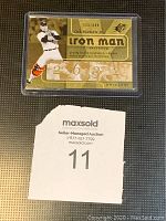 Gold-colored Cal Ripken Jr. Upper Deck SPx Iron Man trading card in protective plastic case, numbered 116/699, featuring pitching image, Orioles logo and Iron Man title.