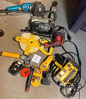 Image showing all 13 items including Makita grinder, Milwaukee drill, Noma power bar, gloves, and measuring tools spread on floor