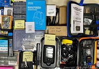 Top view of assorted hobby and outdoors items including fish finder, air pump, hearing protection, and various tools organized in cases and boxes.