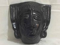 Front view of black clay mask showing facial details and earrings