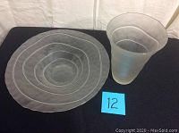 Photo showing two frosted glass items - a conical shaped vase and a shallow bowl with concentric circular designs.