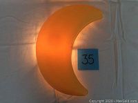 Lit yellow crescent moon-shaped wall light showing warm glow.