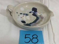 View of the ceramic pour dish showing the handle, spout, and the glaze pattern inside the bowl.